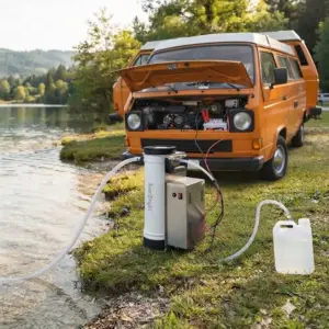 Aqua Peak 190 transportabelt osmoseanlæg placeret ved siden af en VW folkevognsbus, hvor de medfølgende 12V klemmetænger er monteret direkte på bilens batteri.